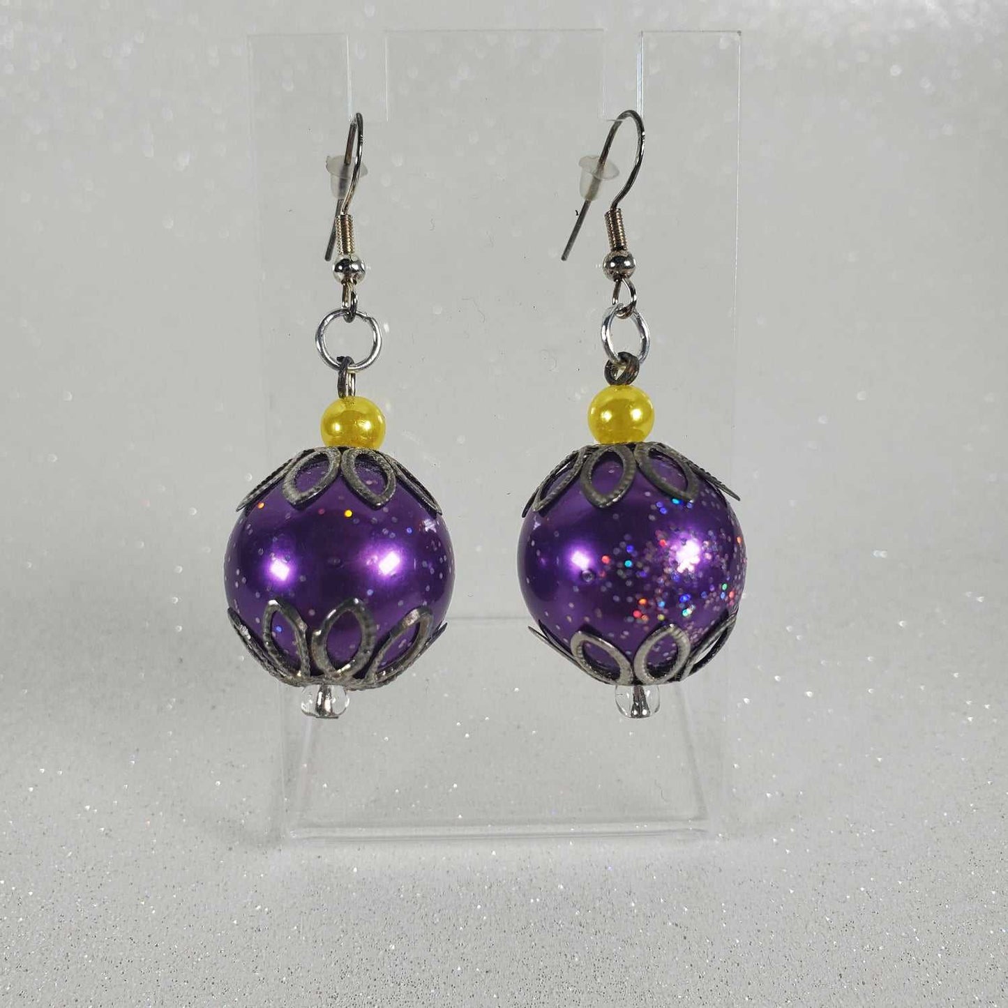 Purple beaded earrings with silver accents on a white background