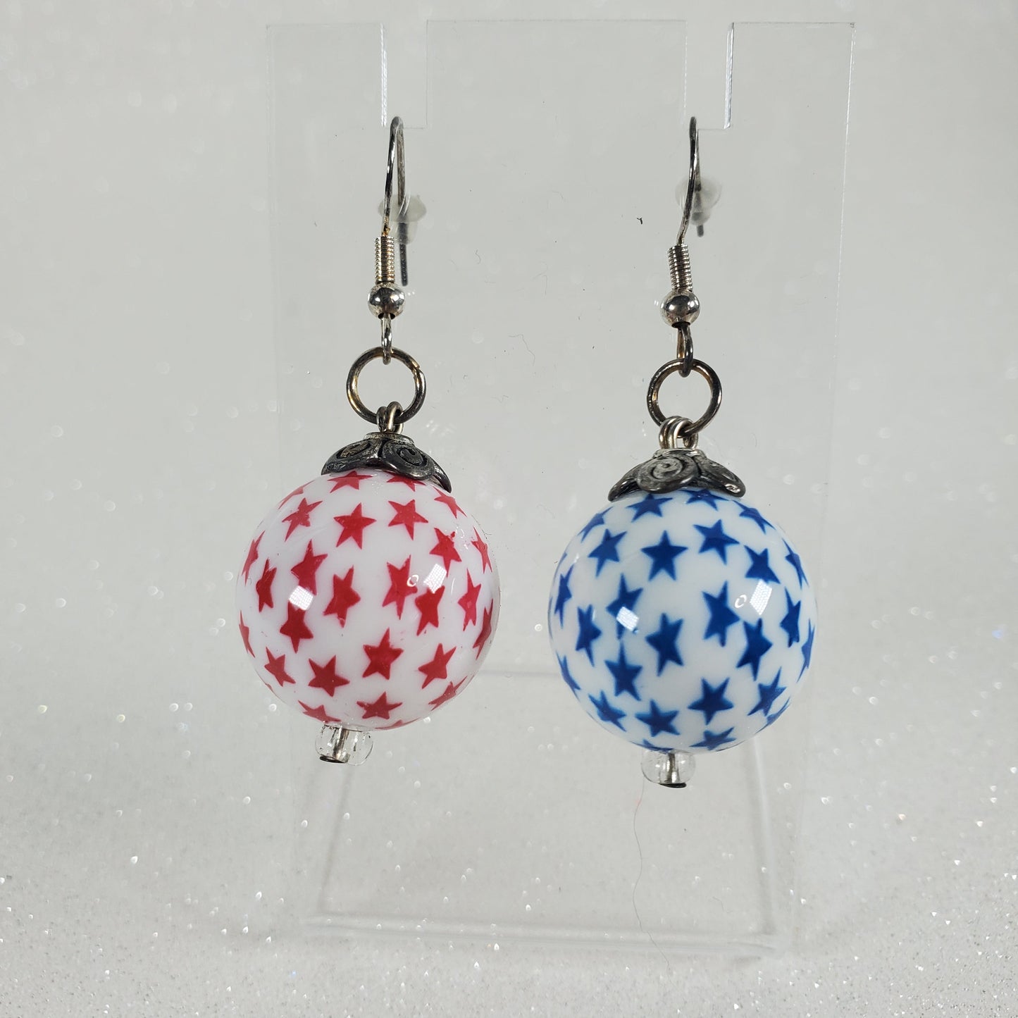 Pair of earrings with star-patterned spherical beads on a white background