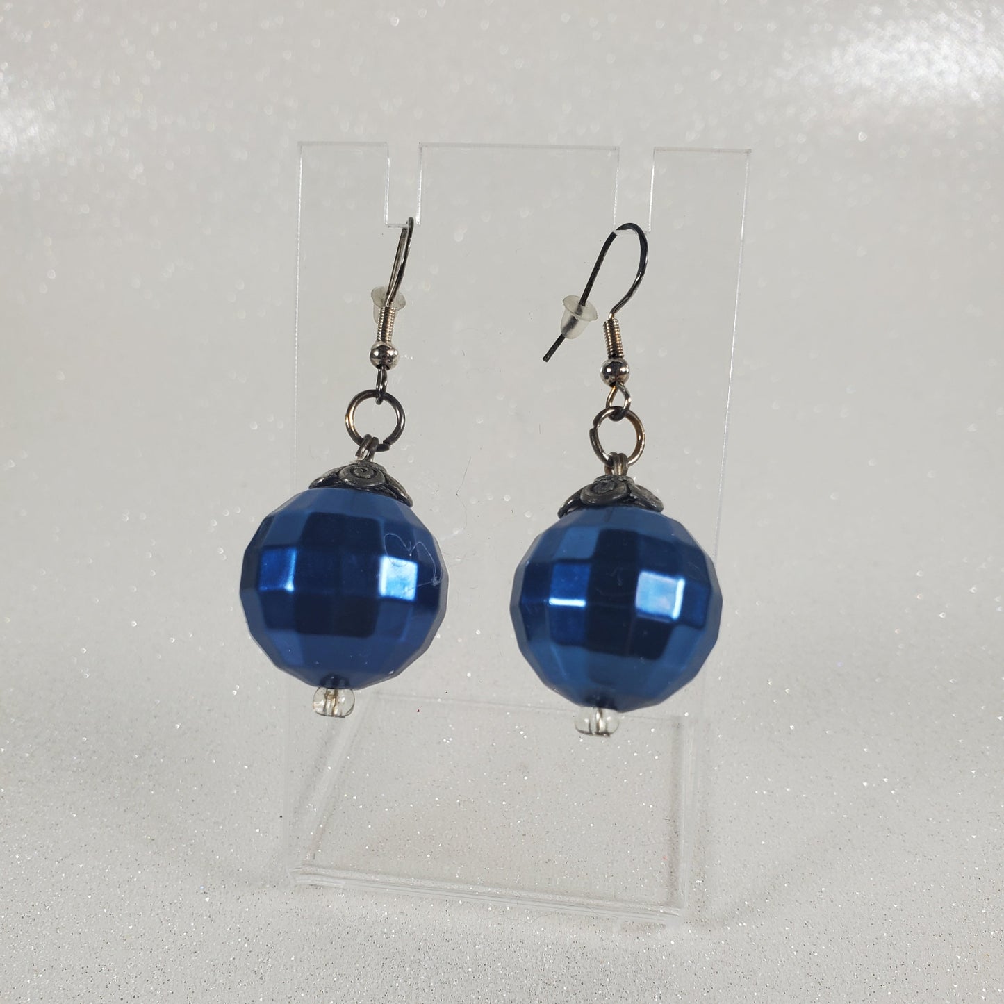 Blue beaded earrings on a clear plastic sheet with a white background