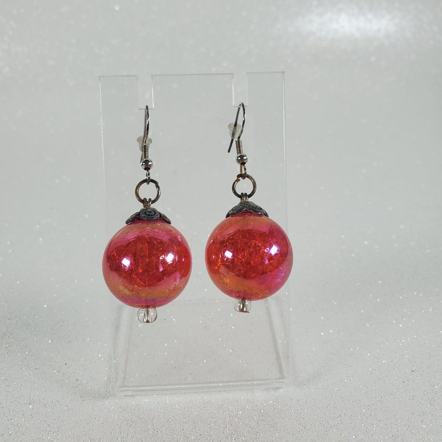 Pair of red beaded earrings on a clear card with a white background