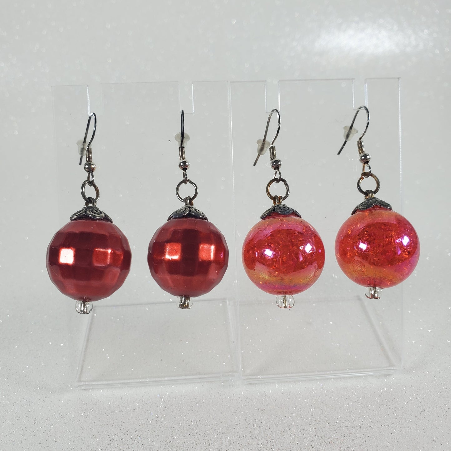 Set of red glass bead earrings on a clear card against a light gray background