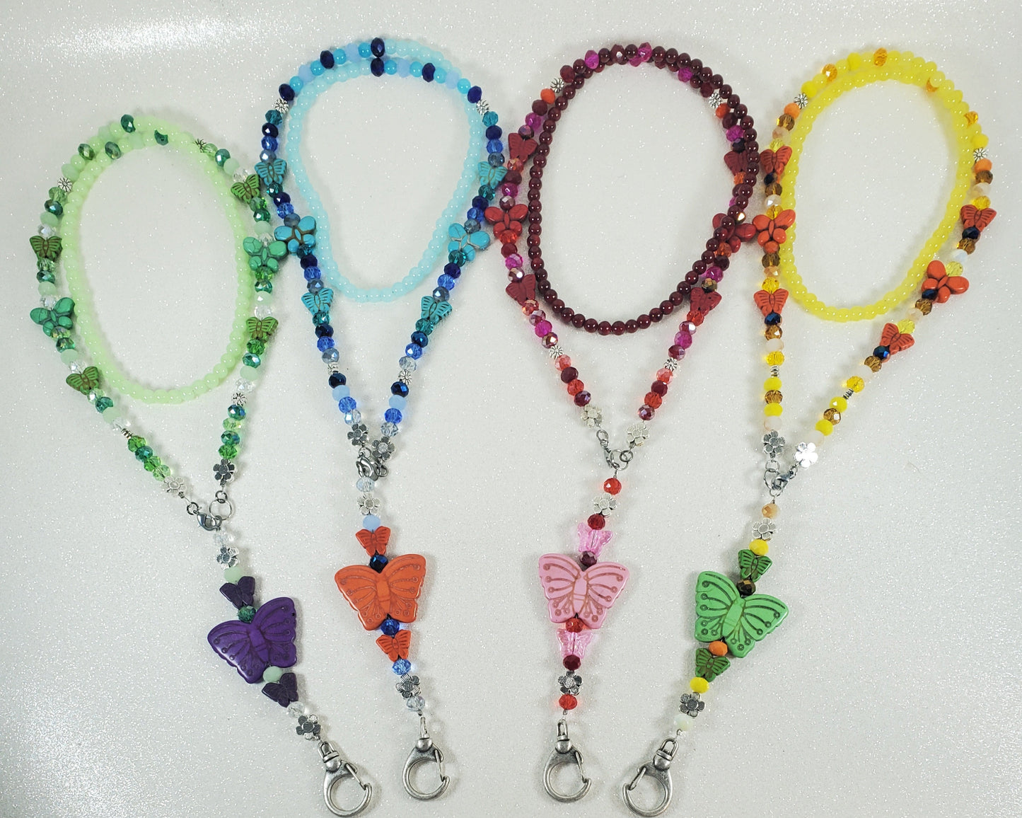 Set of colorful beaded lanyards with butterfly charms on a white background