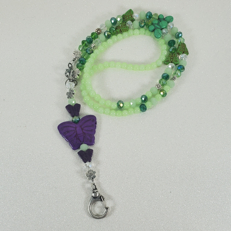 Beaded lanyard with a purple butterfly charm on a light gray background