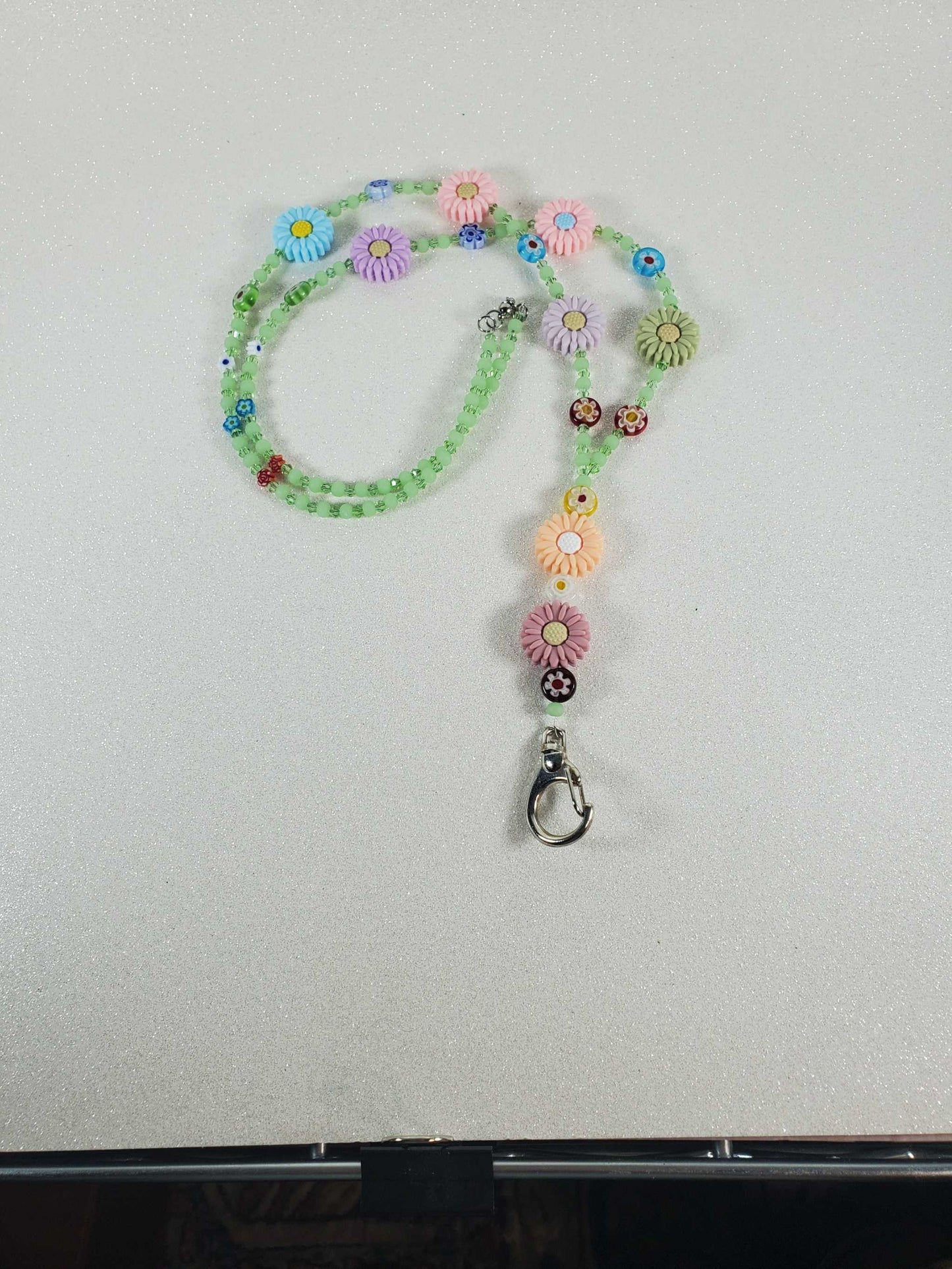 Colorful Daisy Daze lanyard with Millefiori flower beads, polymer daisies, green glass, and Austrian crystals, 30 inches long with a metal clip.