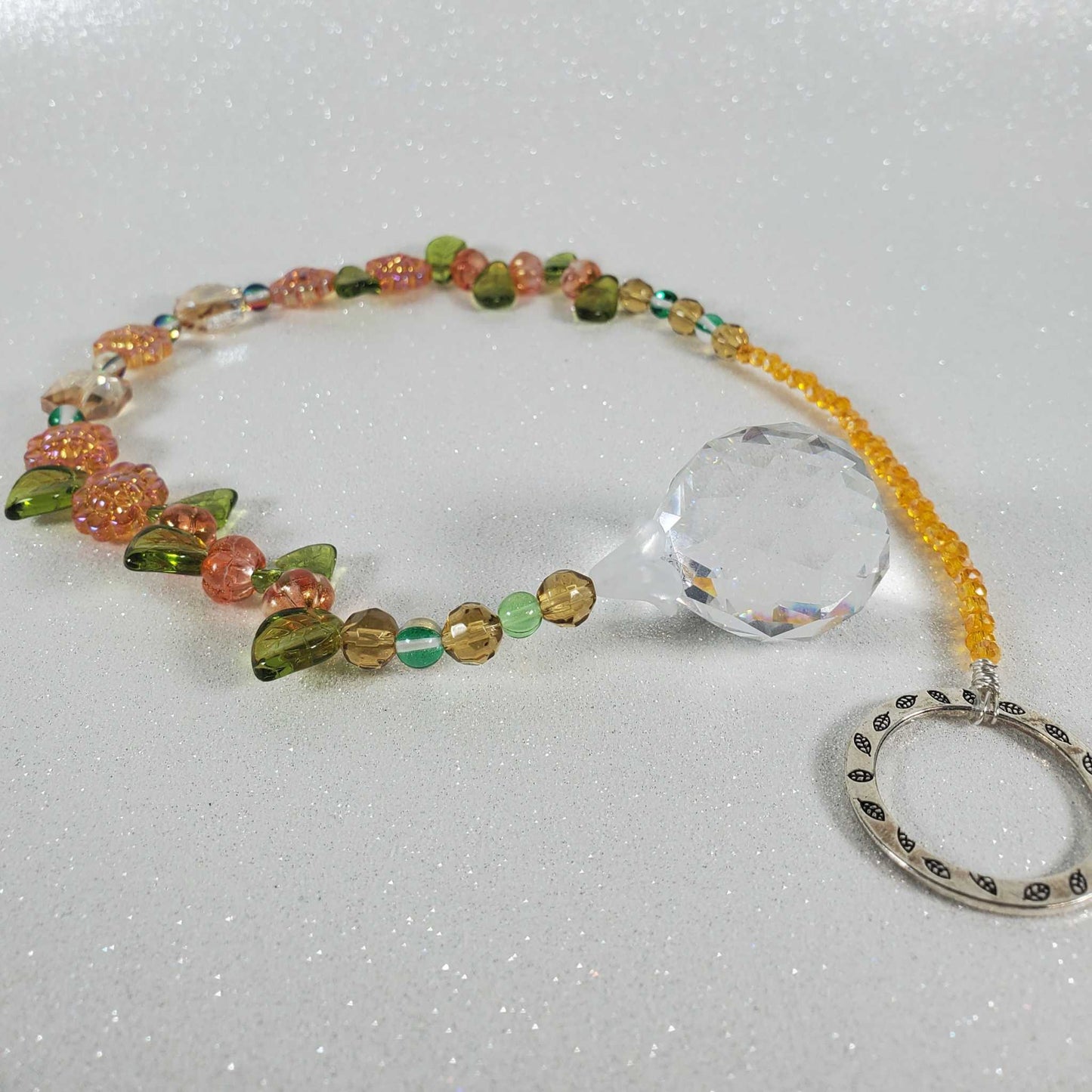 Crystal suncatcher with orange sunflower beads, green glass accents, yellow crystals, and a clear drop prism.