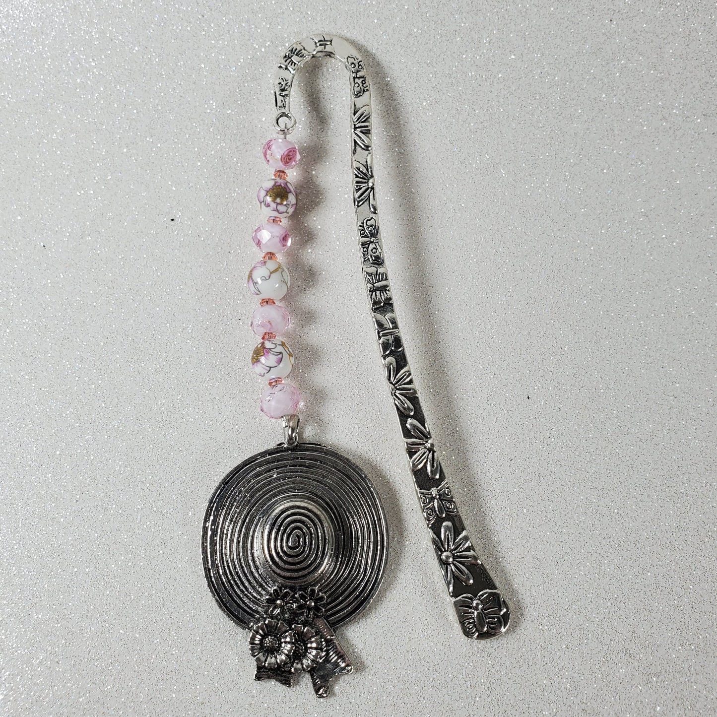 Decorative metal bookmark with floral beads on a gray background