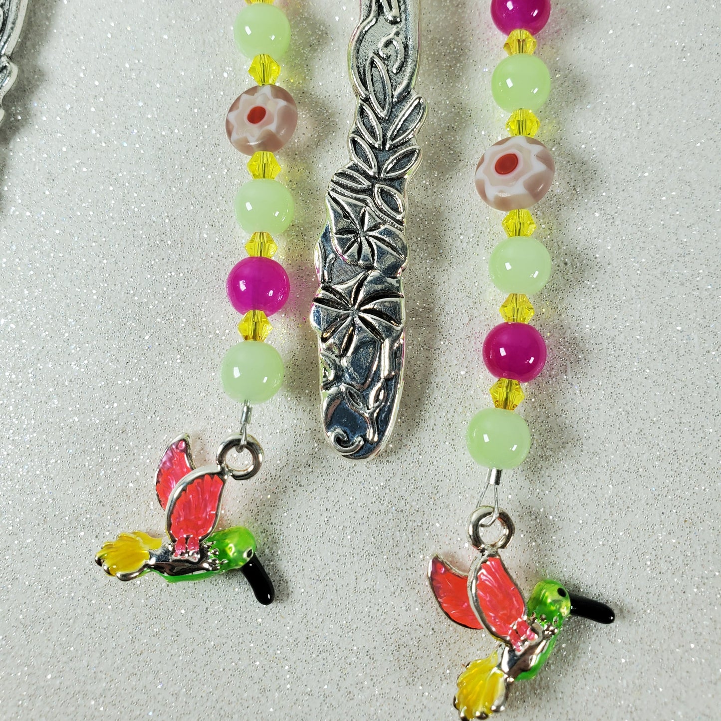 Beaded bookmark with hummingbird charms on a textured surface