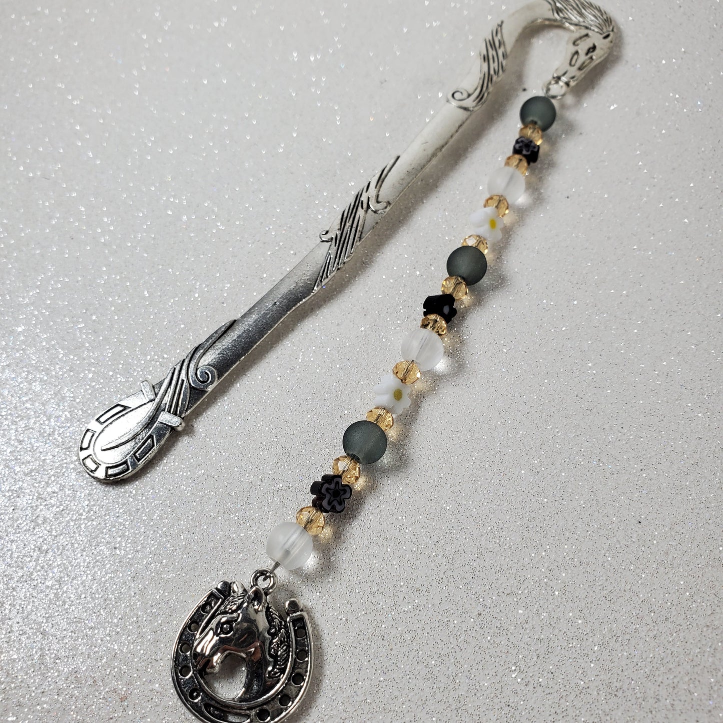 Decorative bookmark with silver glass beads, and horseshoe on a light gray background