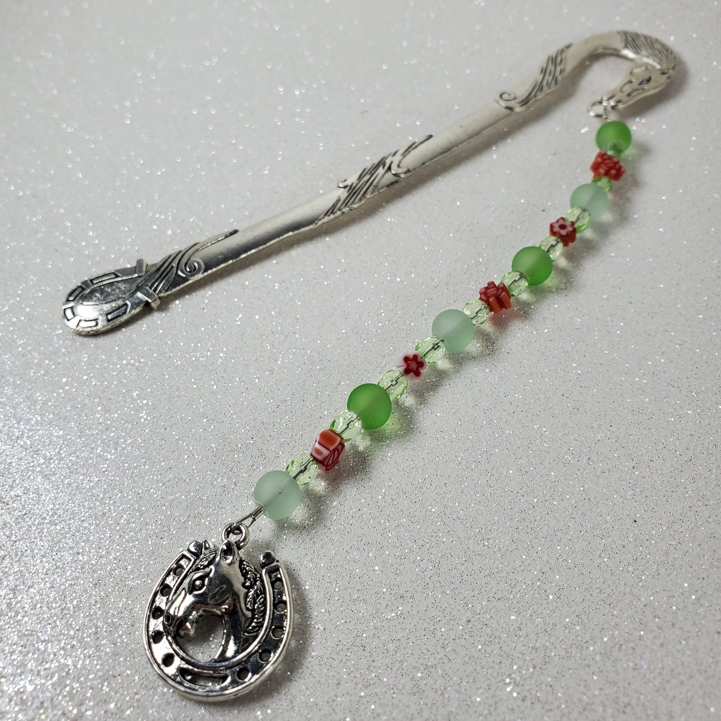 Decorative bookmark with beads and a metal hook on a light gray background