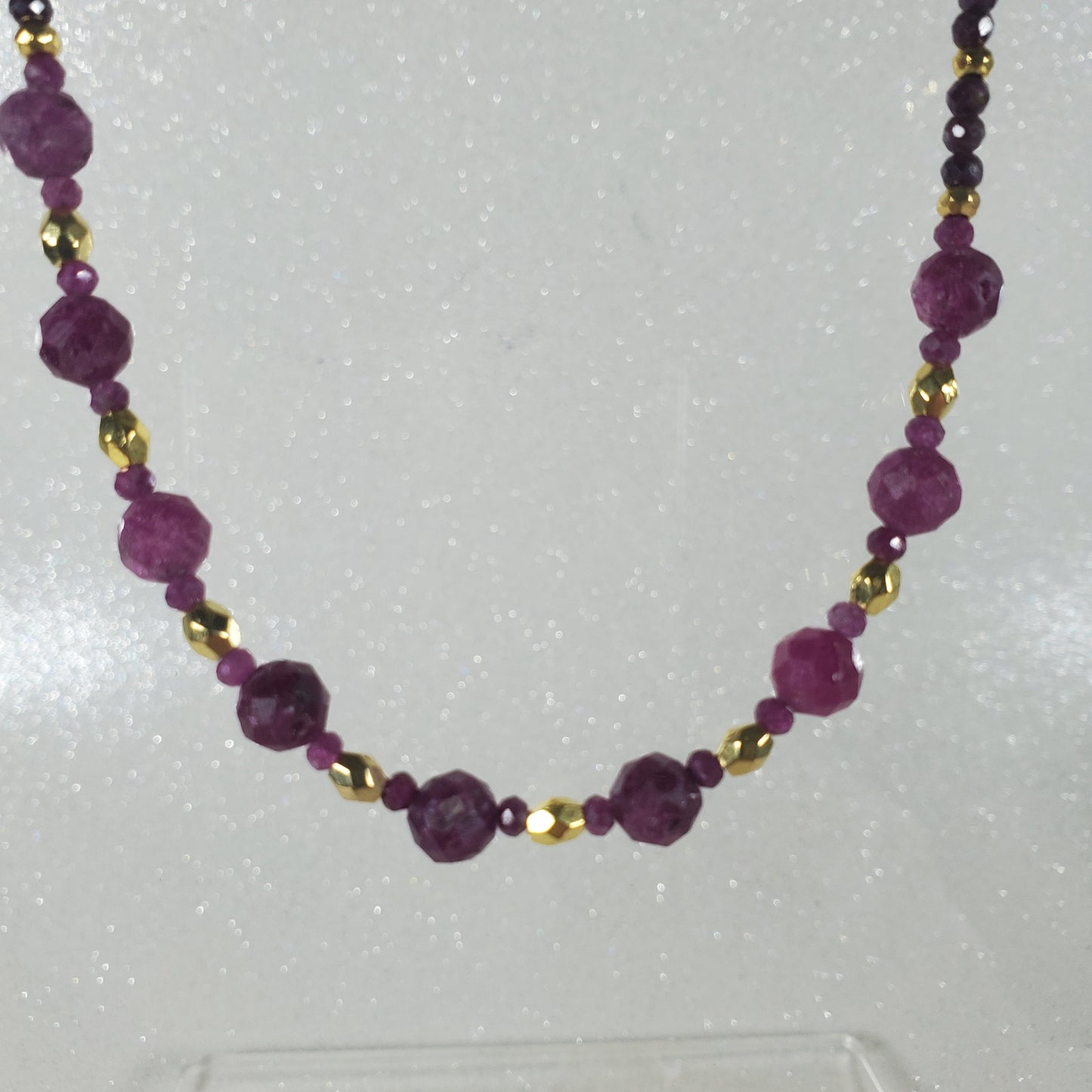 Necklace with Ruby beads and gold accents on a white background