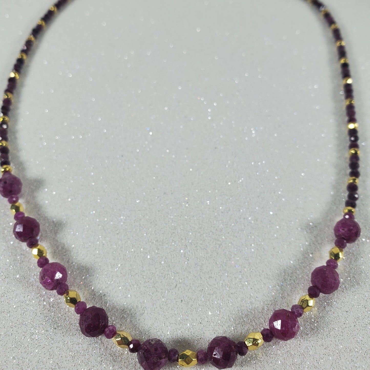 Necklace with Ruby beads and gold accents on a gray background
