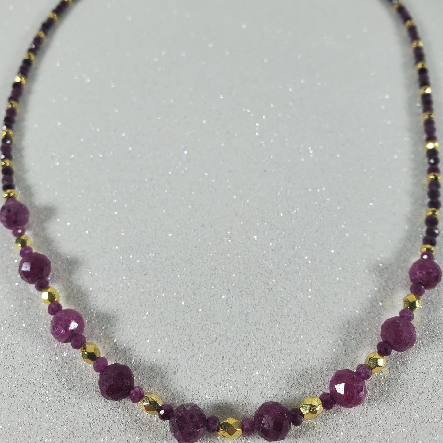 Necklace with Ruby and gold beads on a light gray background