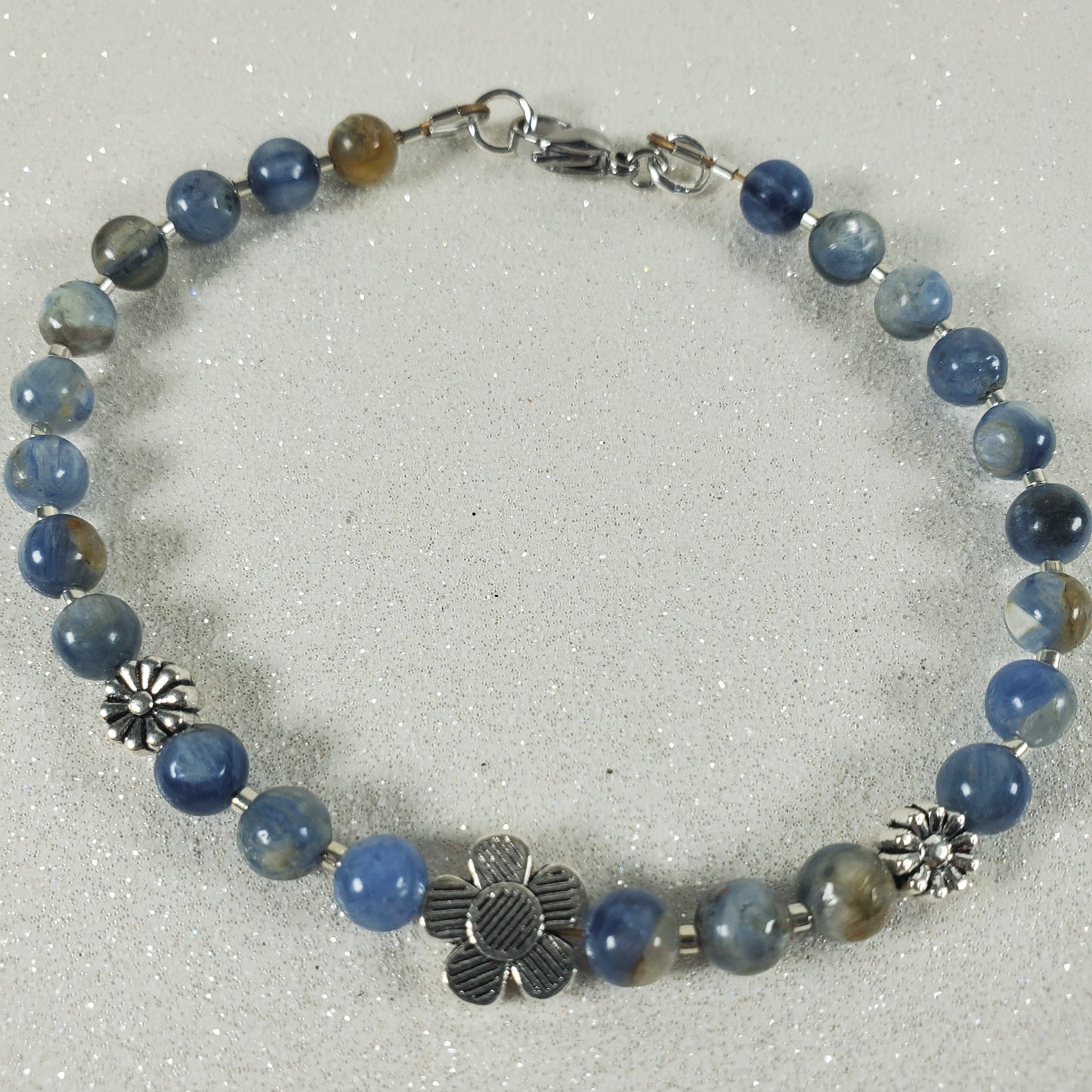 Bracelet with blue gemstone beads and silver charms on a white background