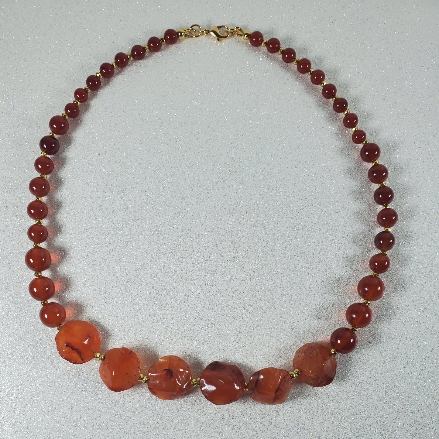 Necklace with red and orange beads on a light gray background