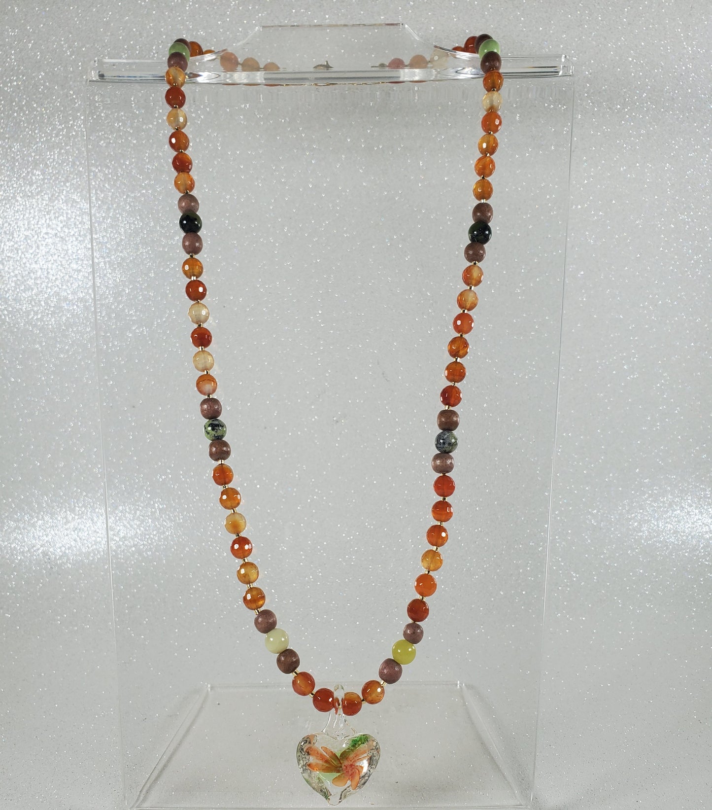 Multicolored bead necklace on a clear stand against a white background