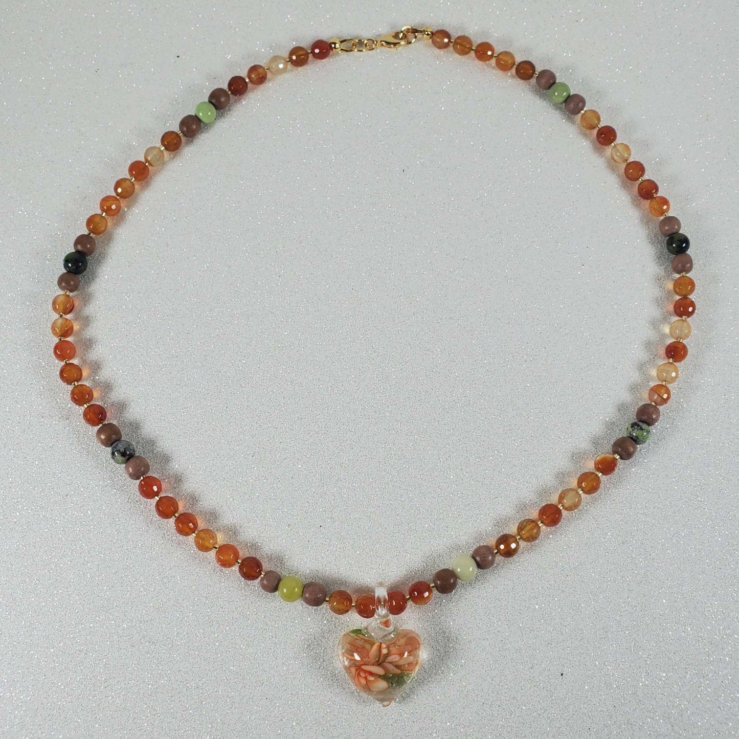 Handcrafted gemstone necklace featuring Carnelian and Serpentine beads with a floral glass heart pendant