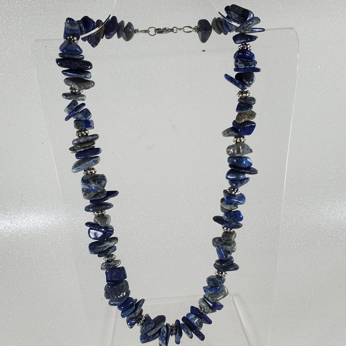 Necklace with blue beads on a clear stand against a white background