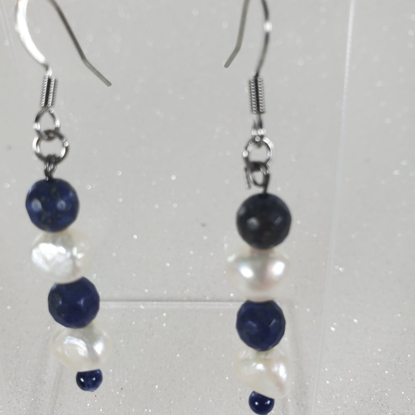 Pair of earrings with blue and white beads on a clear background
