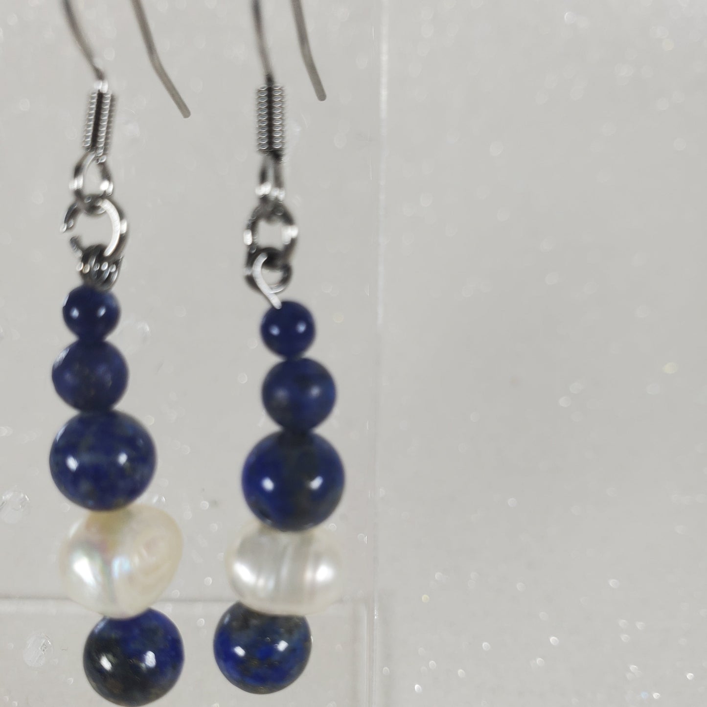 Pair of blue and white beaded earrings on a light gray background