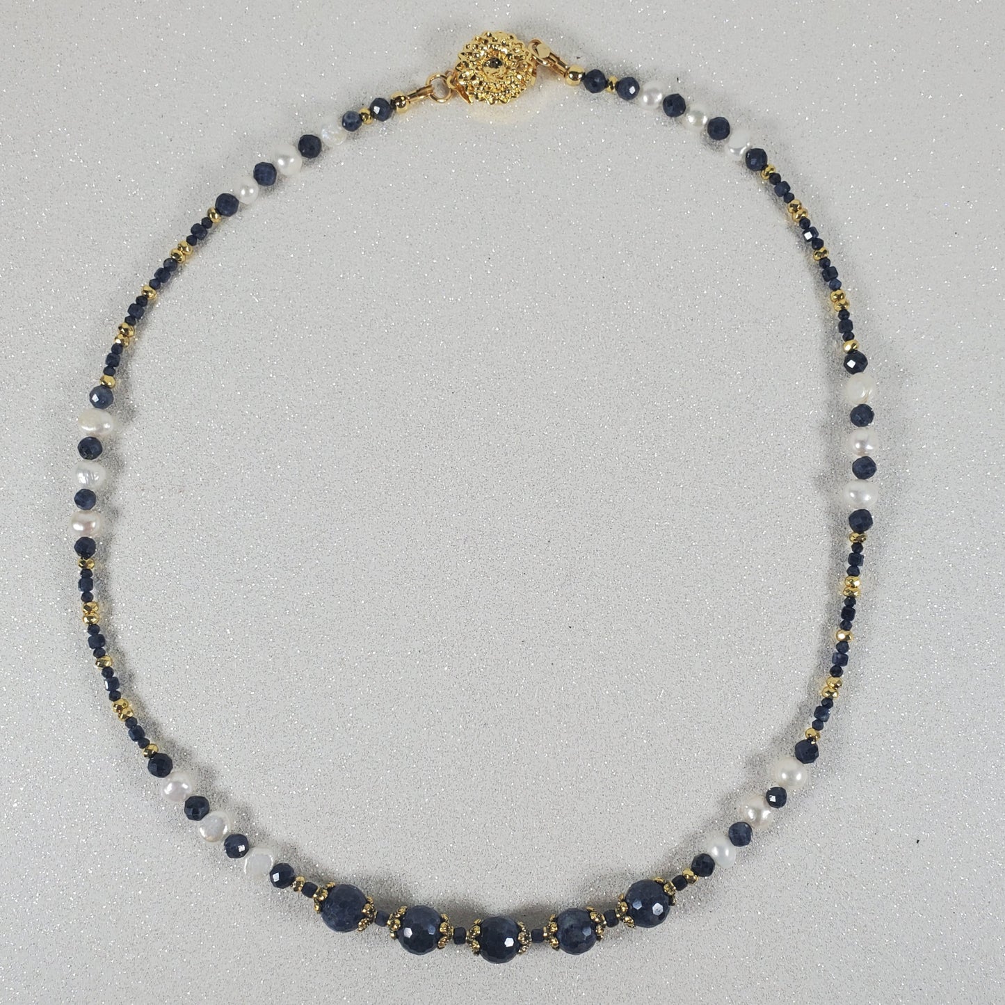 Necklace with blue and gold beads on a light gray background