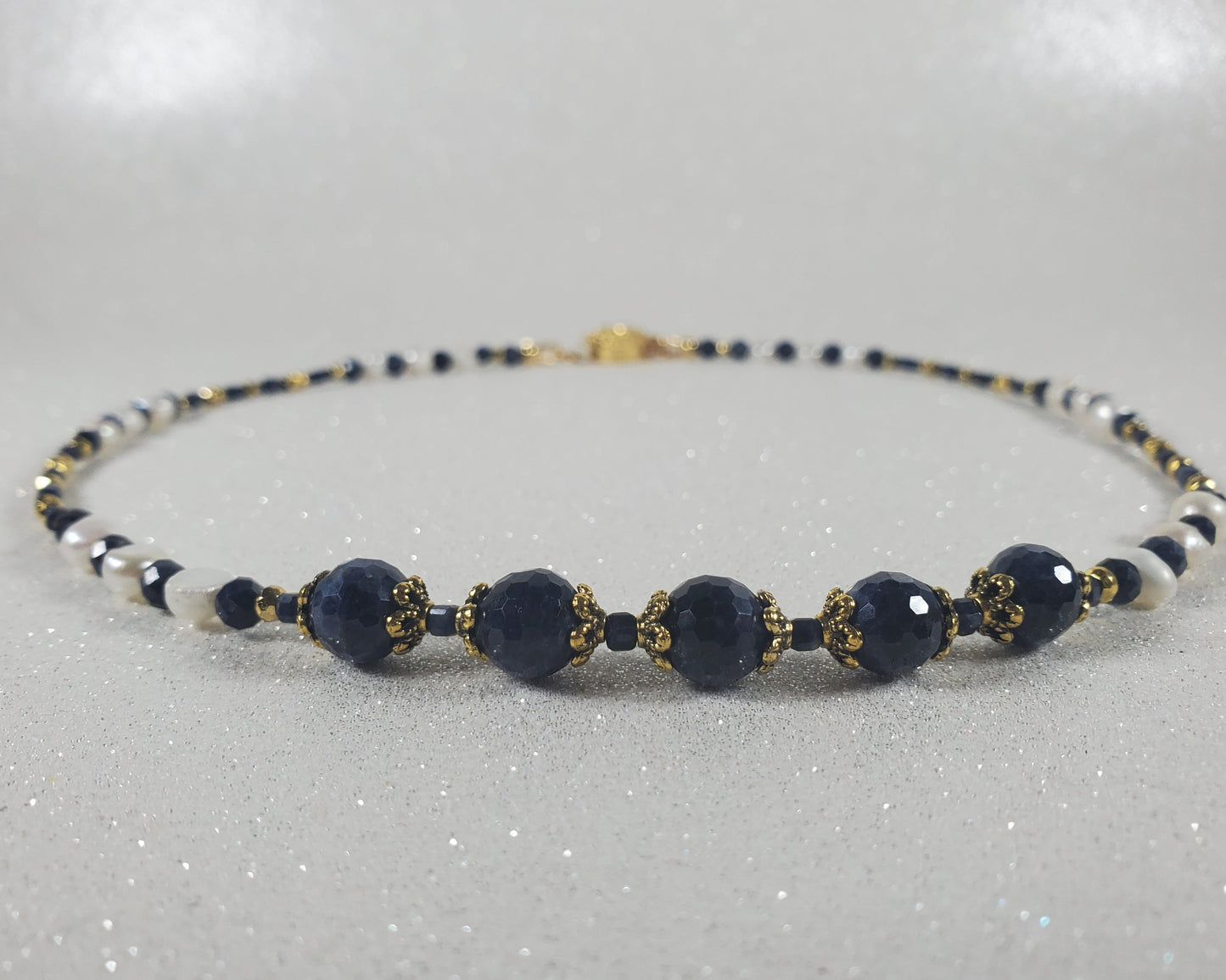Navy blue beaded necklace with gold accents on a light gray background