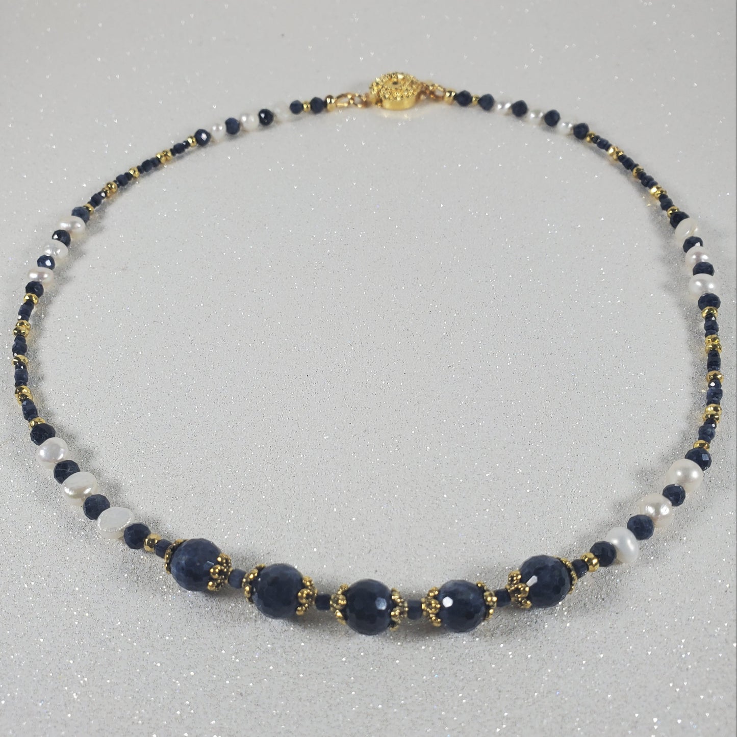 Necklace with blue, white, and gold beads on a gray background
