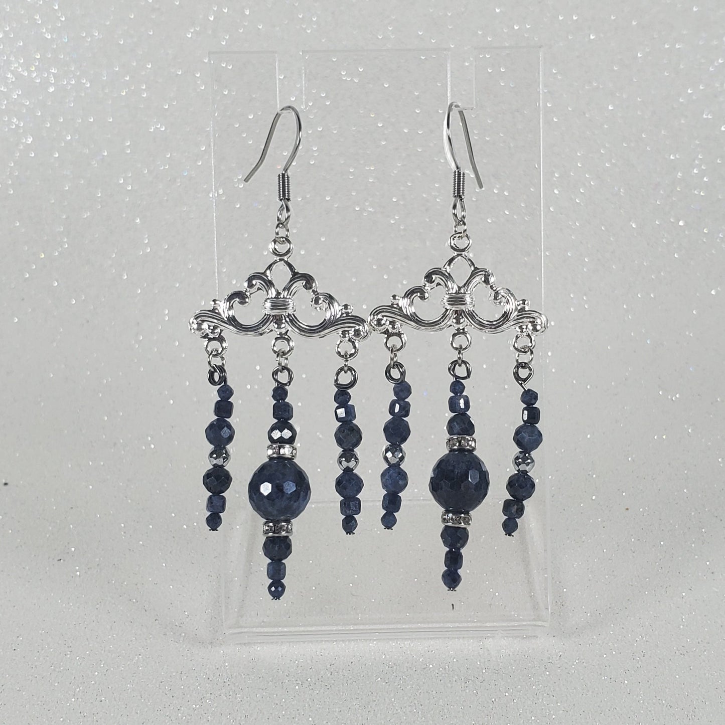 Pair of blue beaded earrings on a clear card against a light gray background