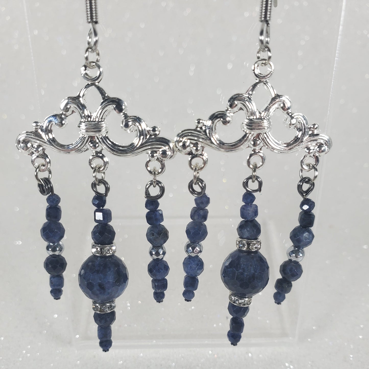 Silver and blue beaded hair accessories on a clear stand against a light gray background