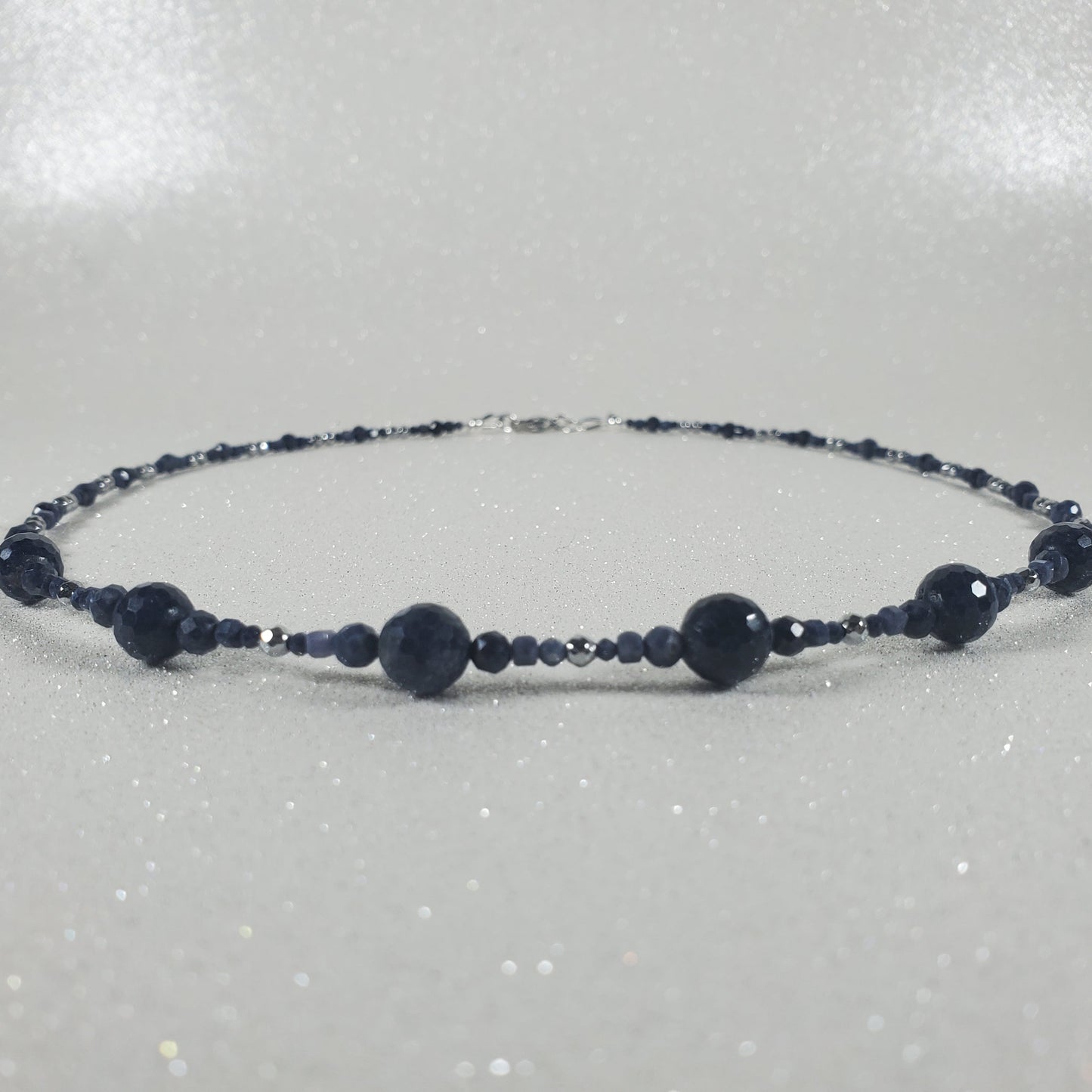 Beaded necklace with dark beads on a light gray background
