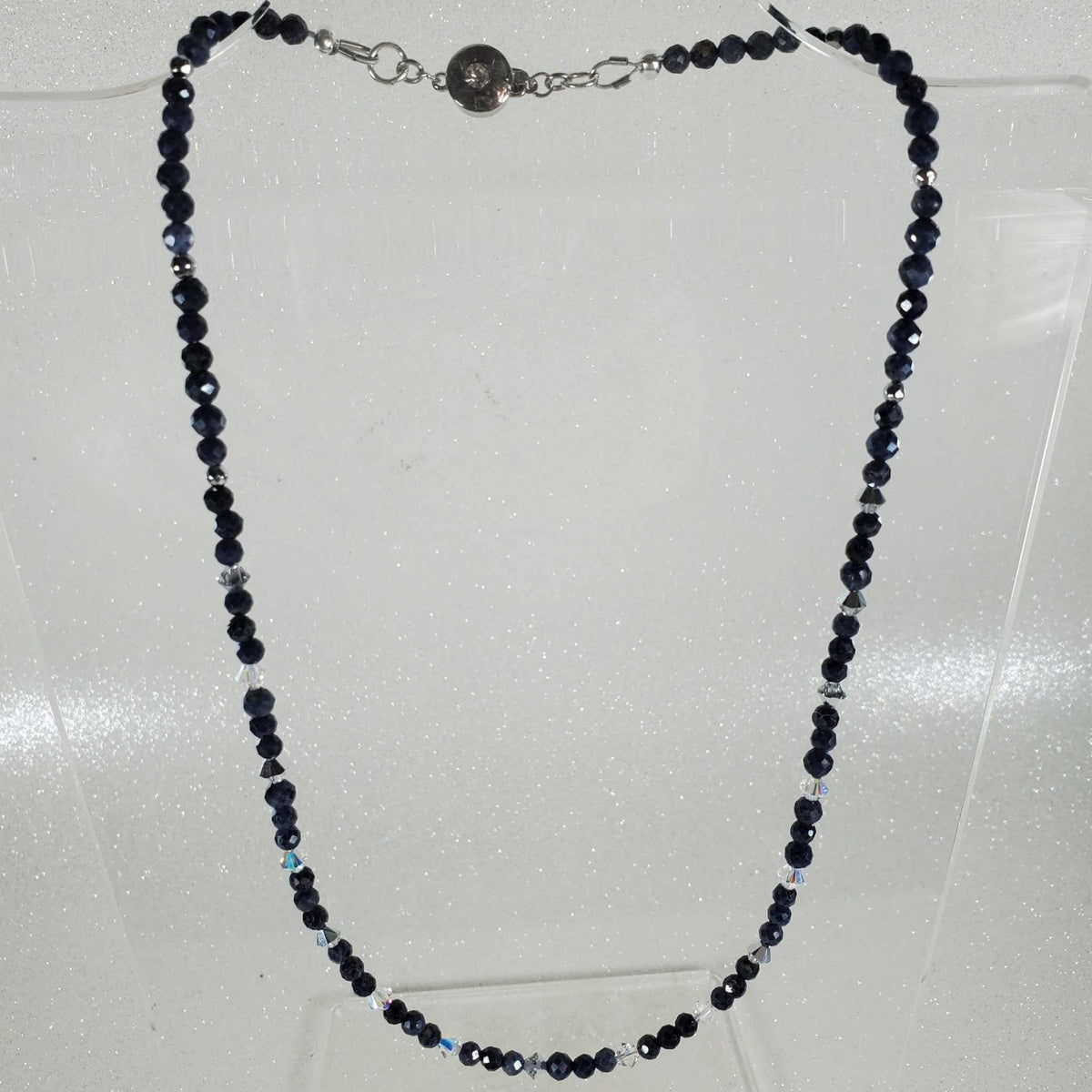 Gemstone Necklace: Sapphire with dark blue faceted beads, silver-tone spacers and a metal clasp, finished with subtle sparkle.