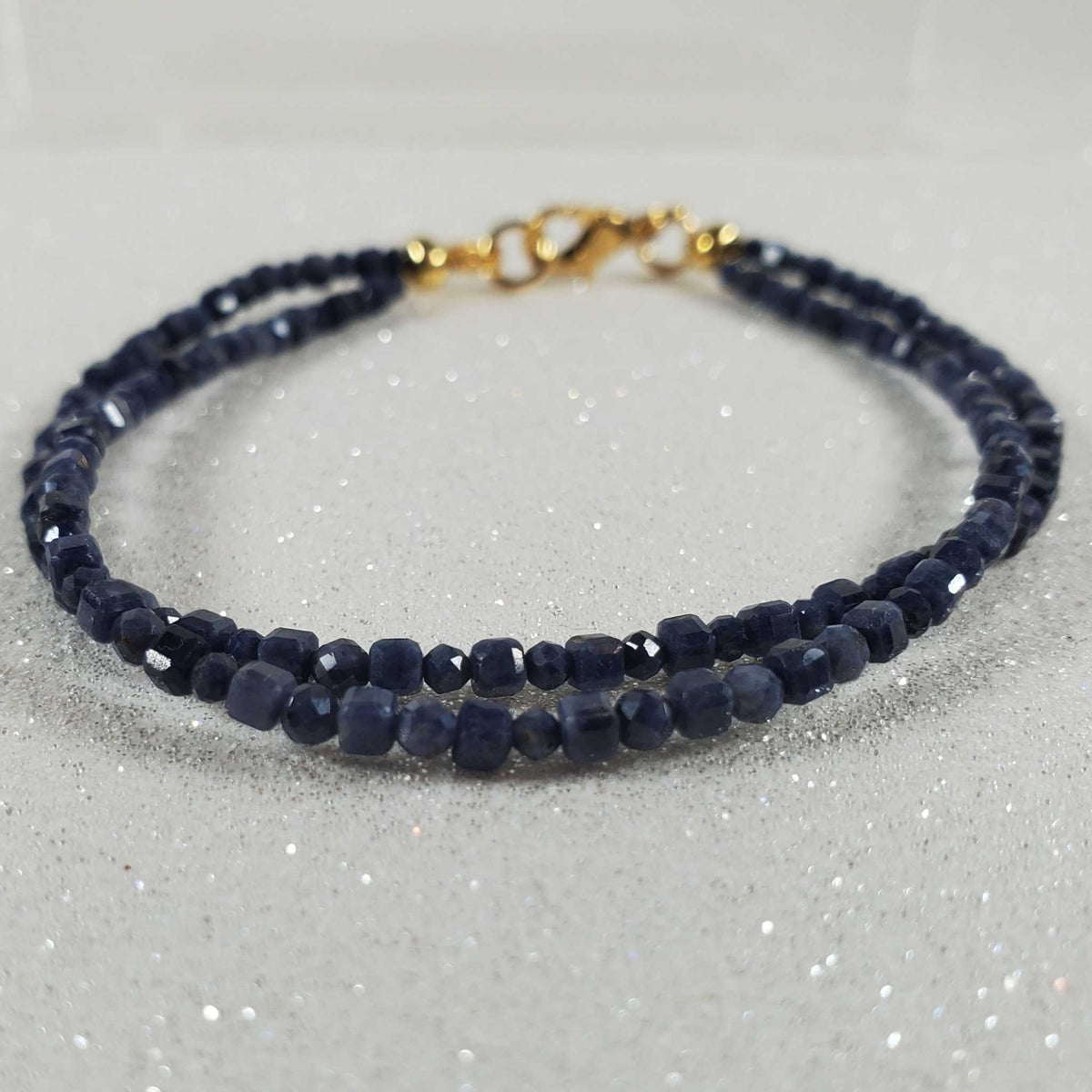 Gemstone Bracelet: Sapphire with two strands of faceted deep navy-blue beads and a gold-tone clasp.