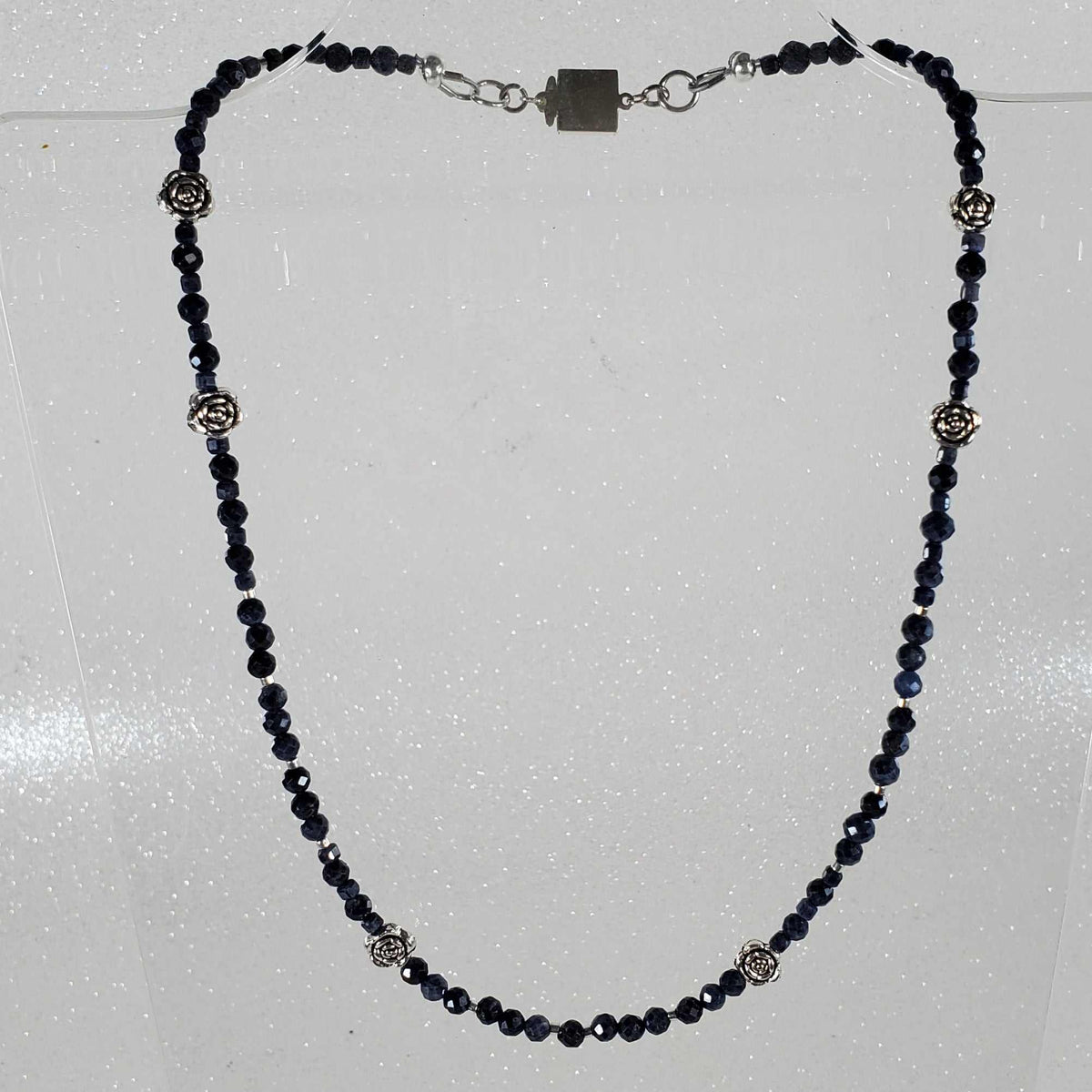 Gemstone Necklace with deep blue faceted beads, silver-toned floral accents, and a box clasp with extension chain.