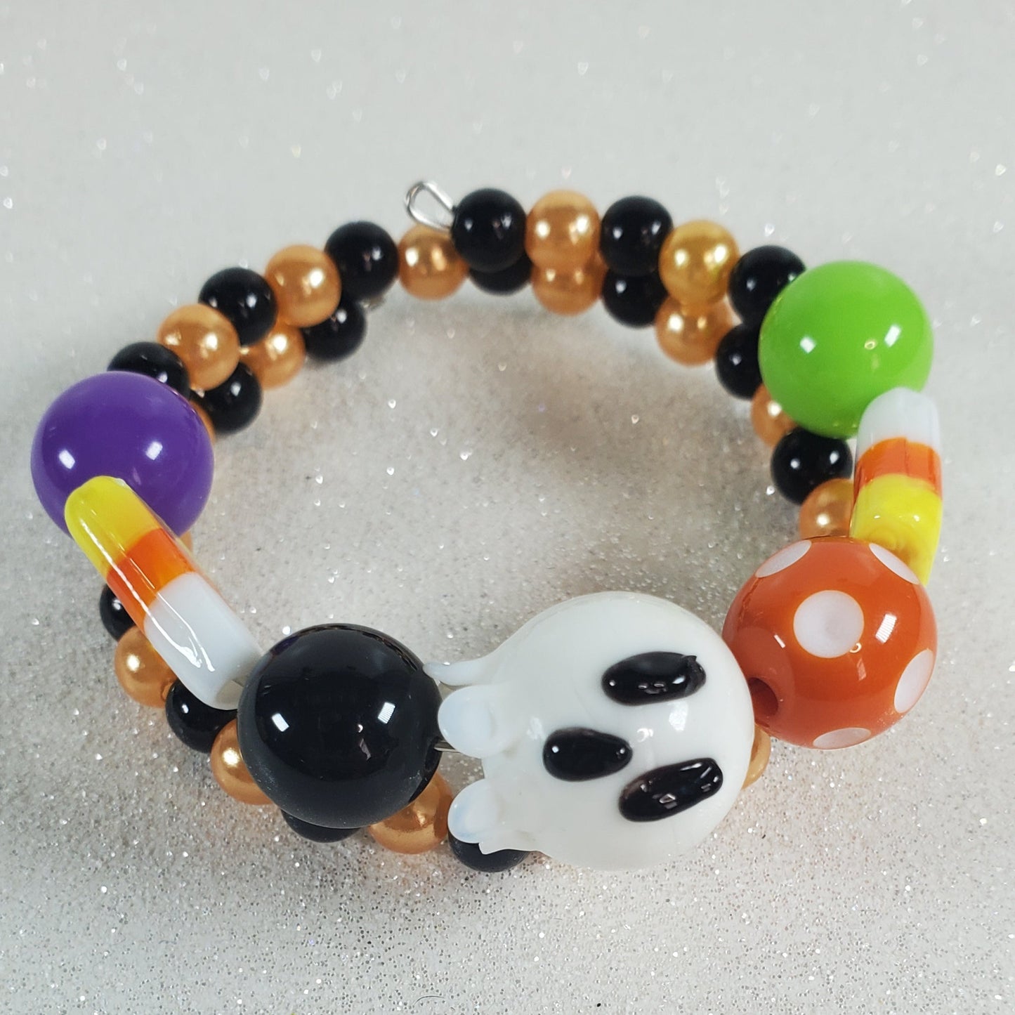 Colorful beaded bracelet with a ghost charm on a light gray background
