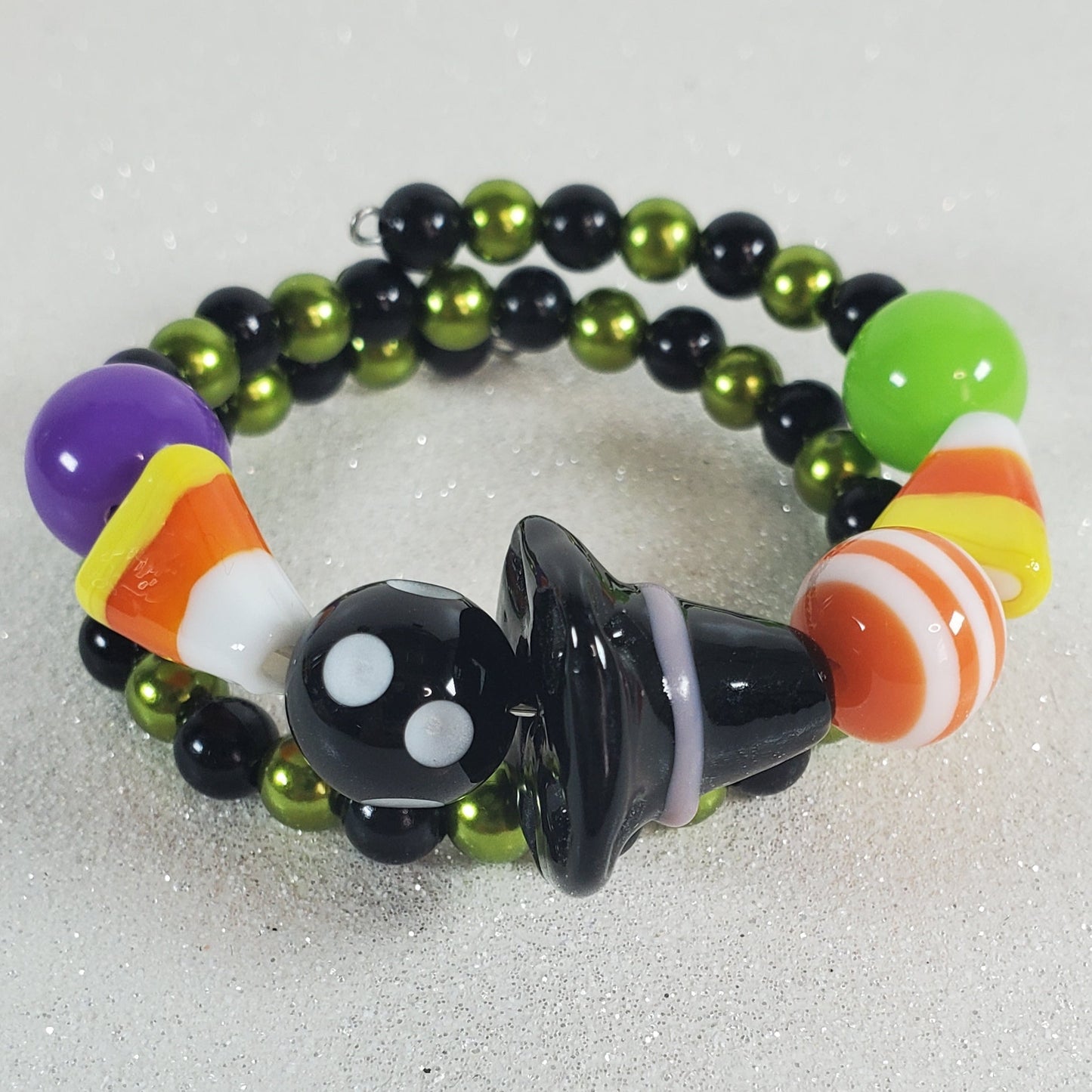 Colorful beaded bracelet with witch hat and candy corn charm on a light gray background
