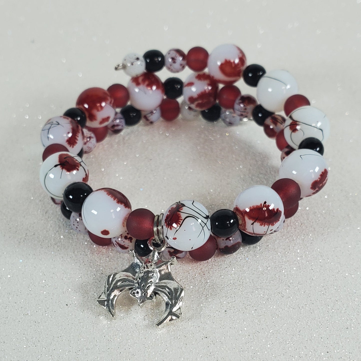 Beaded bracelet with red, white, and black beads on a light gray background