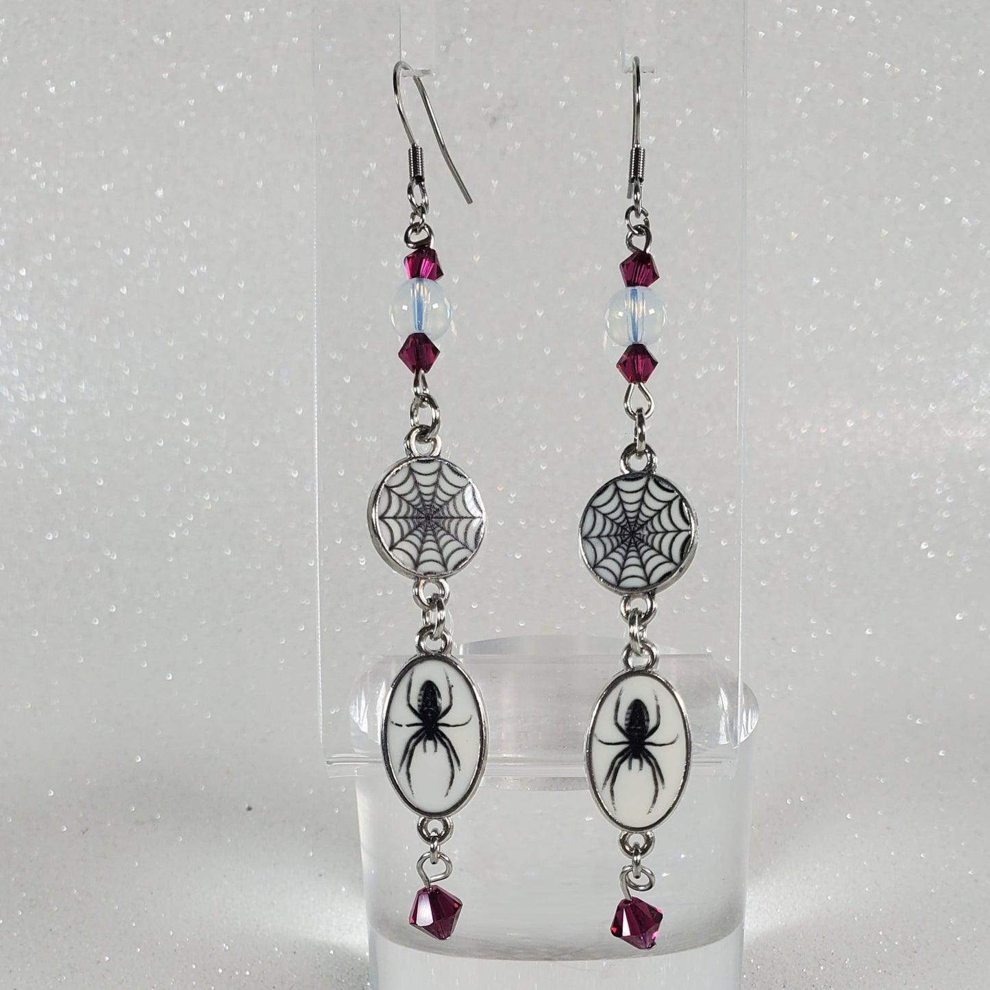 Pair of earrings with spider and web design on a clear background