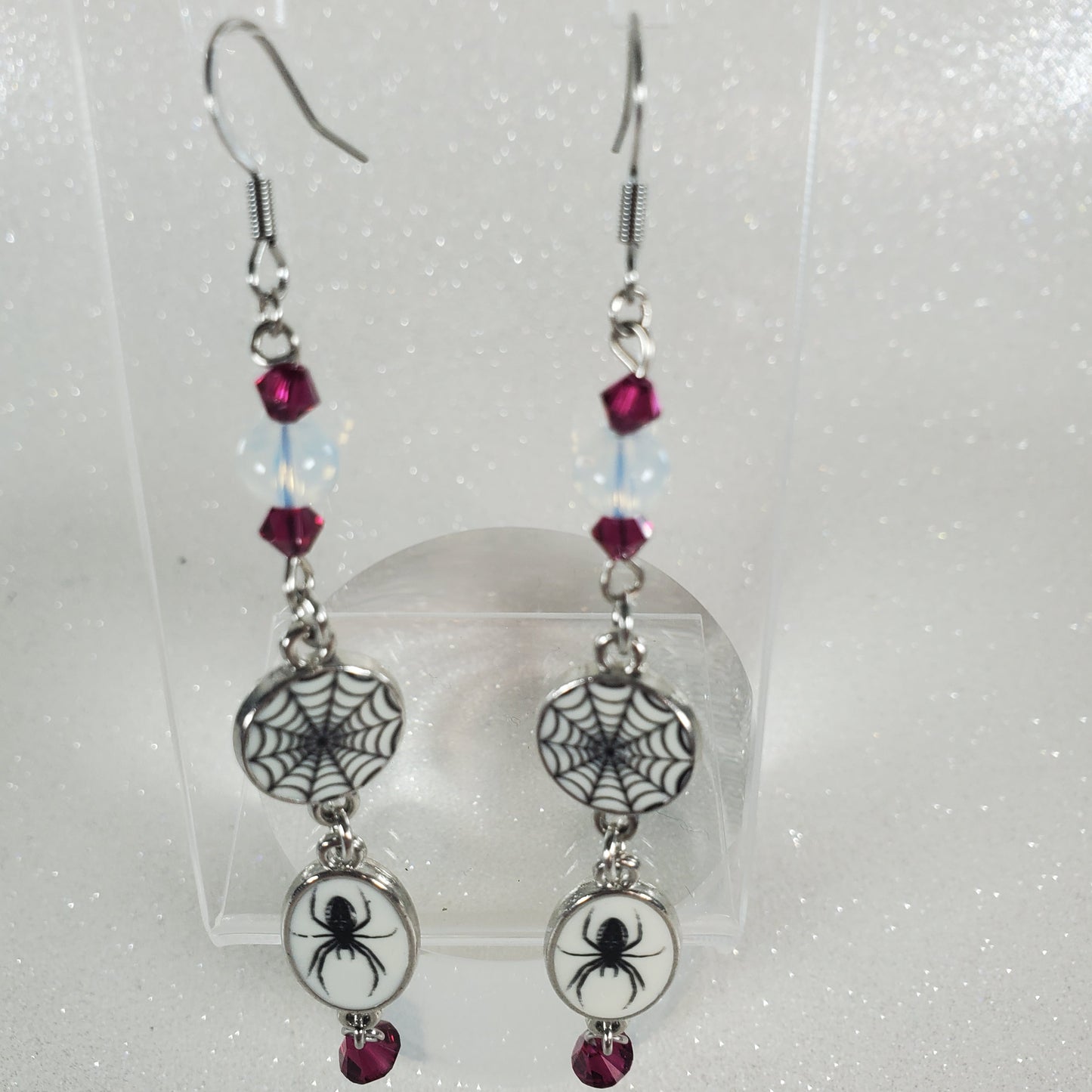 Pair of earrings with spider and web designs on a white background