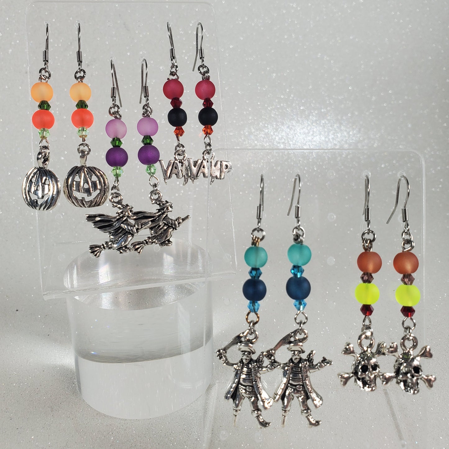 Set of earrings with colorful beads on a clear stand against a white background