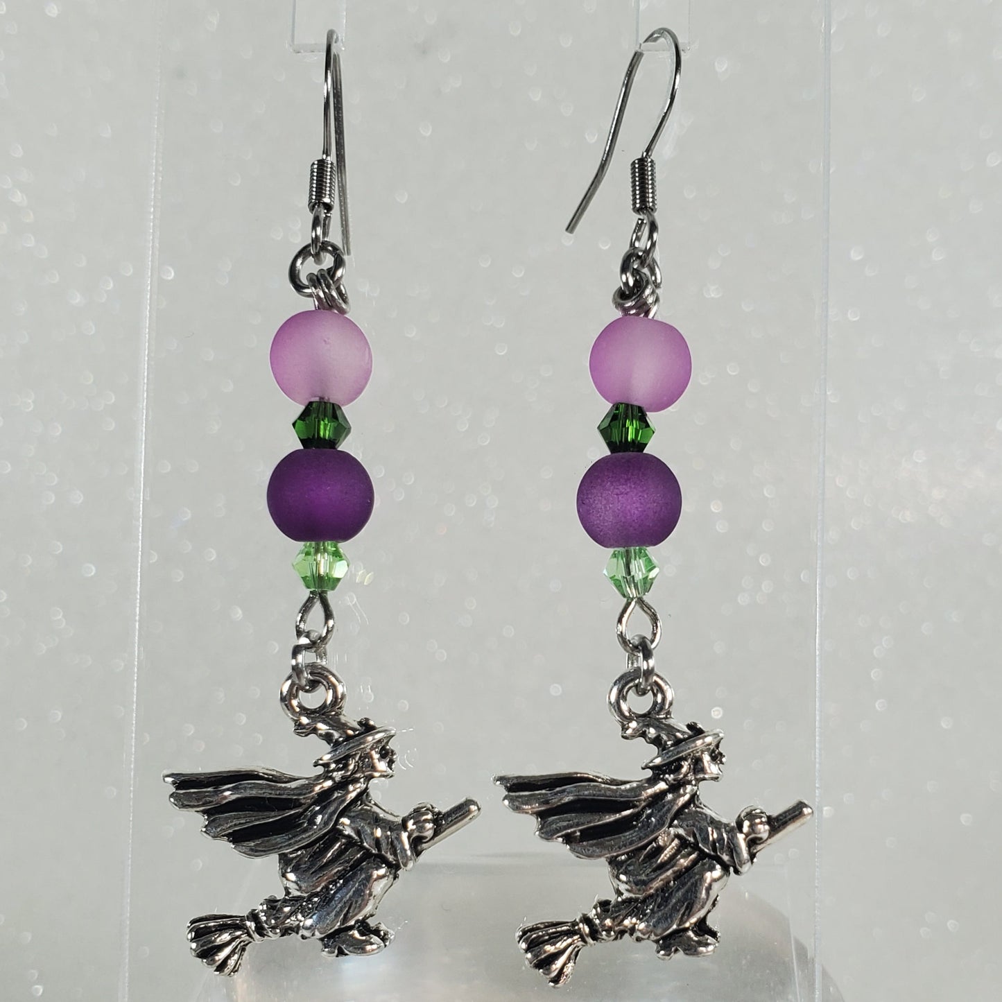 Pair of earrings with purple beads and silver charms on a white background