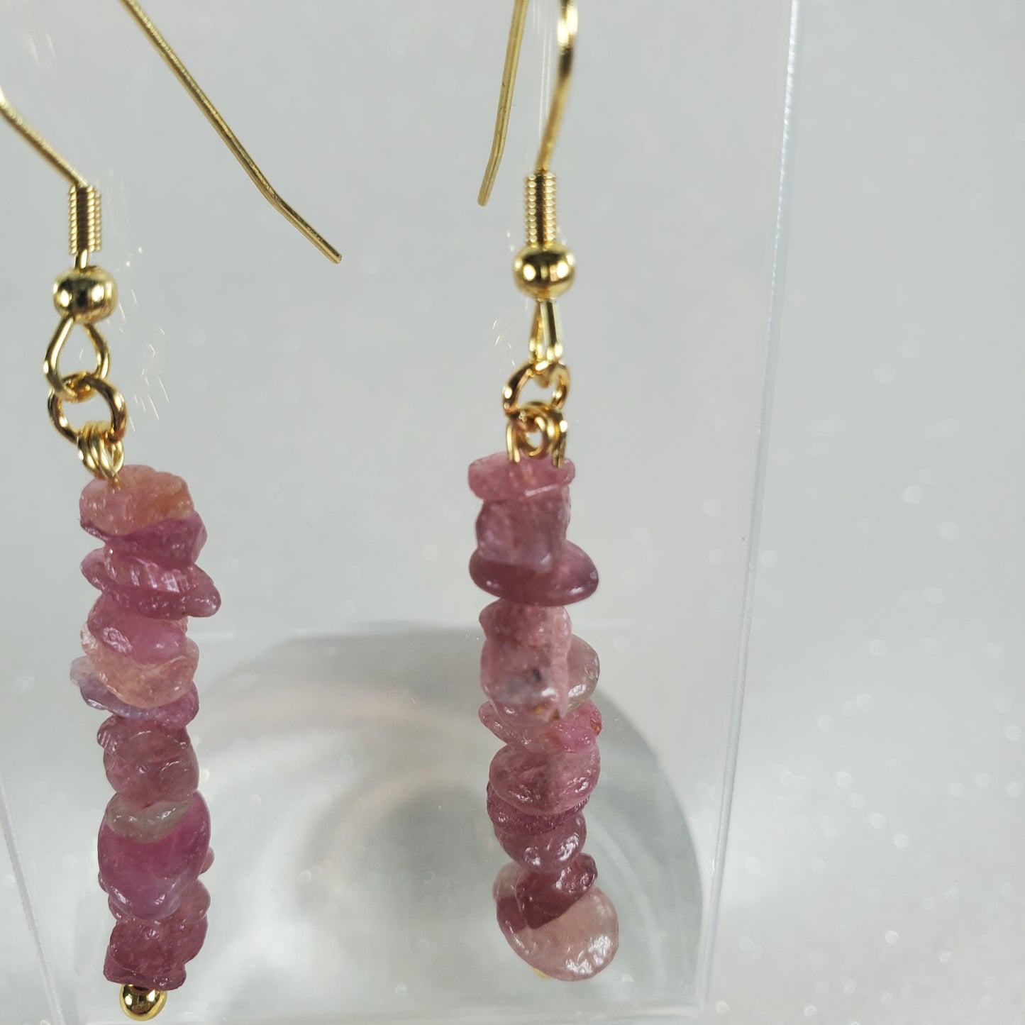 Pink beaded earrings with gold hooks on a white background