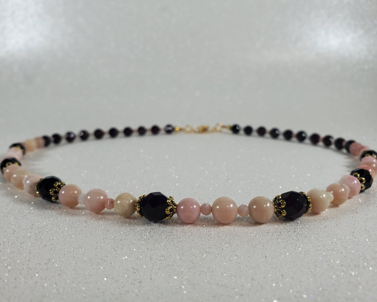 Beaded necklace with pink, red, and gold beads on a white background