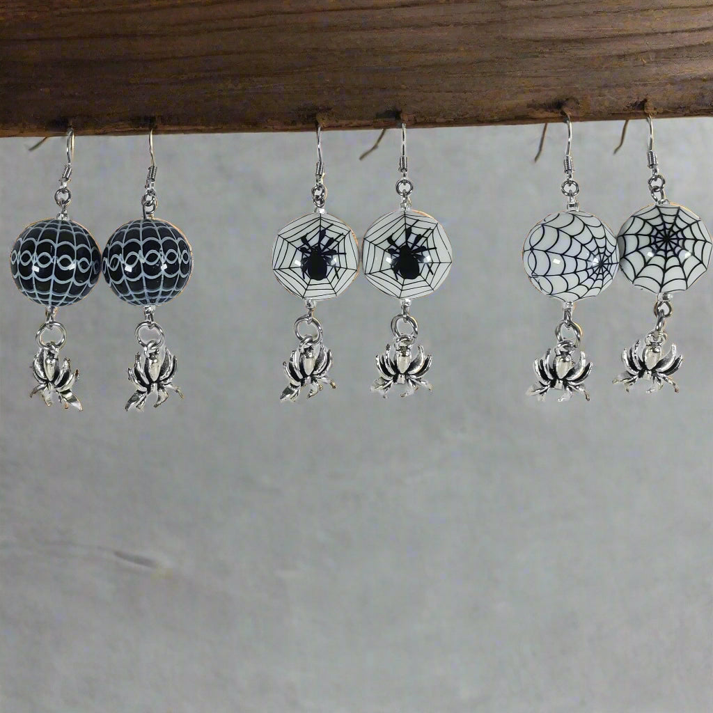 Pair of Halloween-themed earrings with spider webs and spiders on a white card.