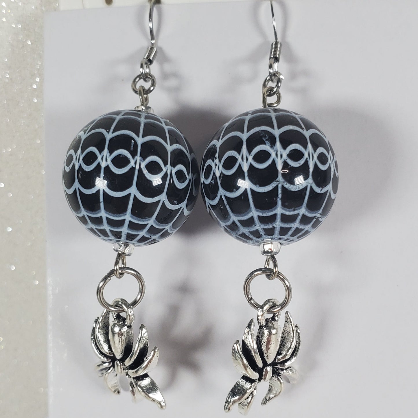 Pair of earrings with black and white patterned beads on a white card.