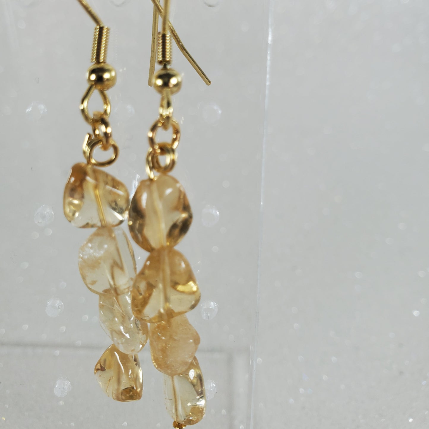 Gold earrings with clear beads on a clear background