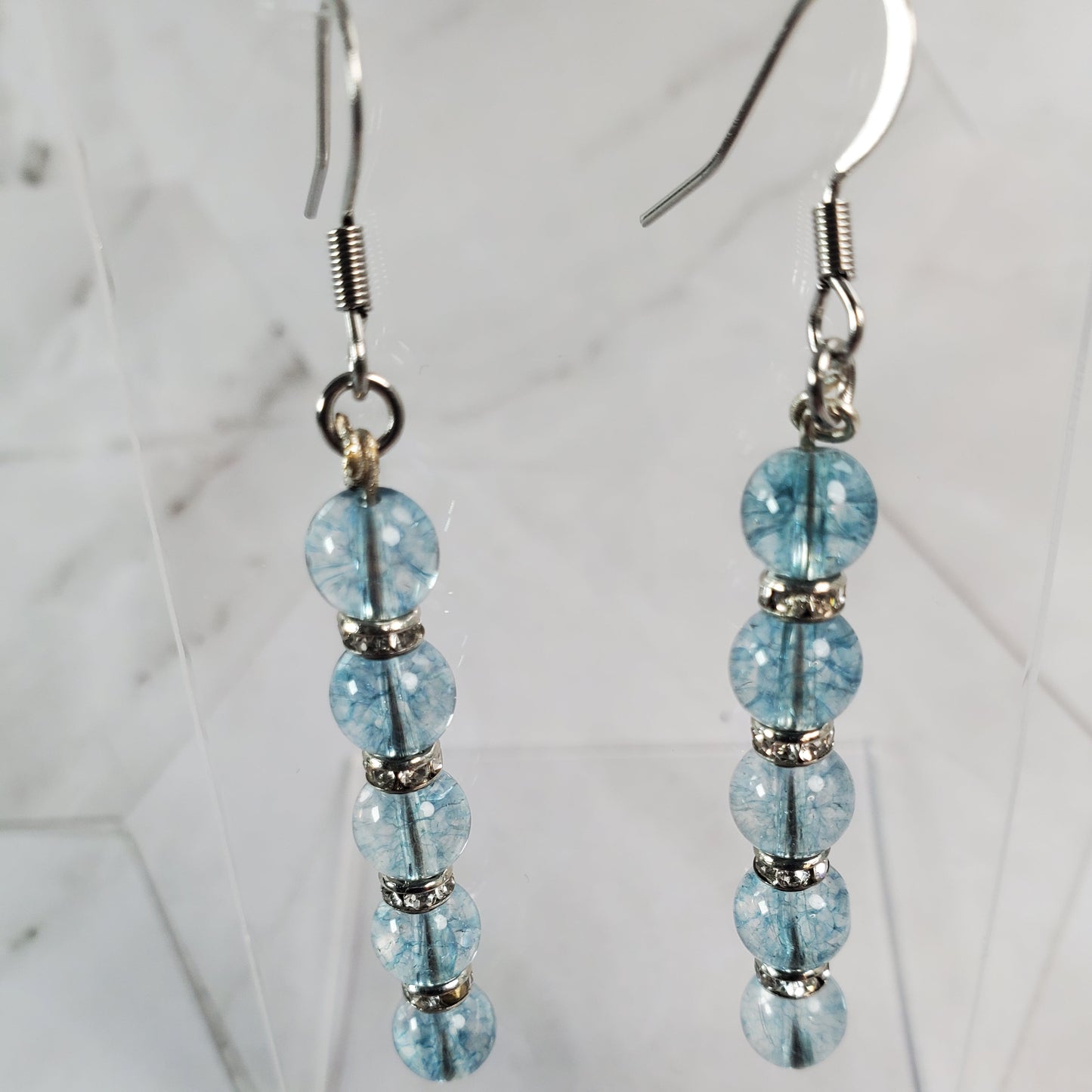 Beaded earrings with blue beads on a white marble background