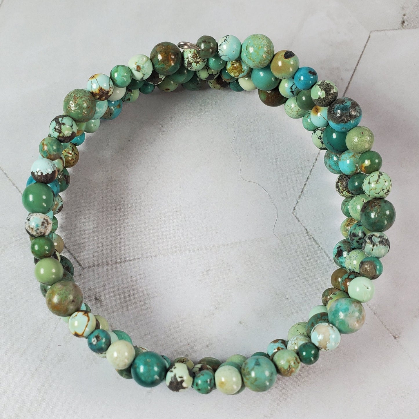 Green beaded bracelet on a light gray tiled floor