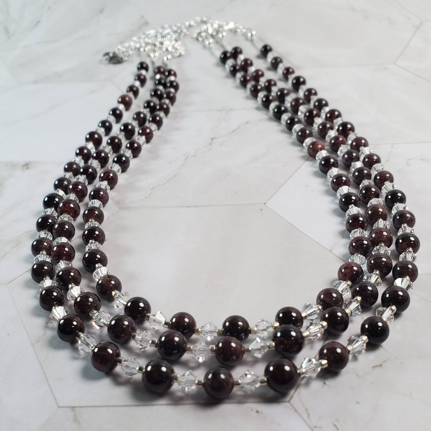 Multistrand necklace with dark beads and clear beads on a marble surface
