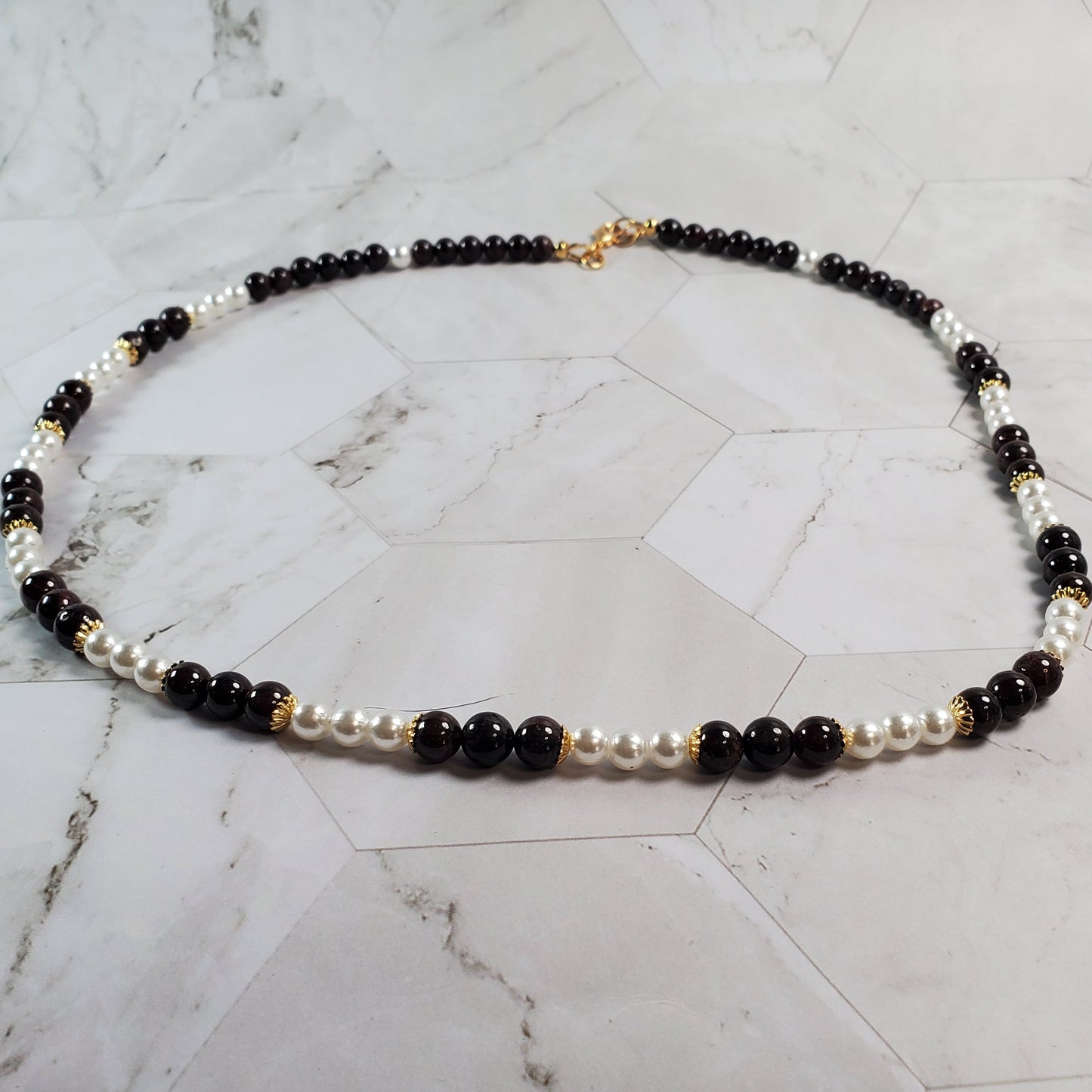 Necklace with Garnet and white beads on a marble surface