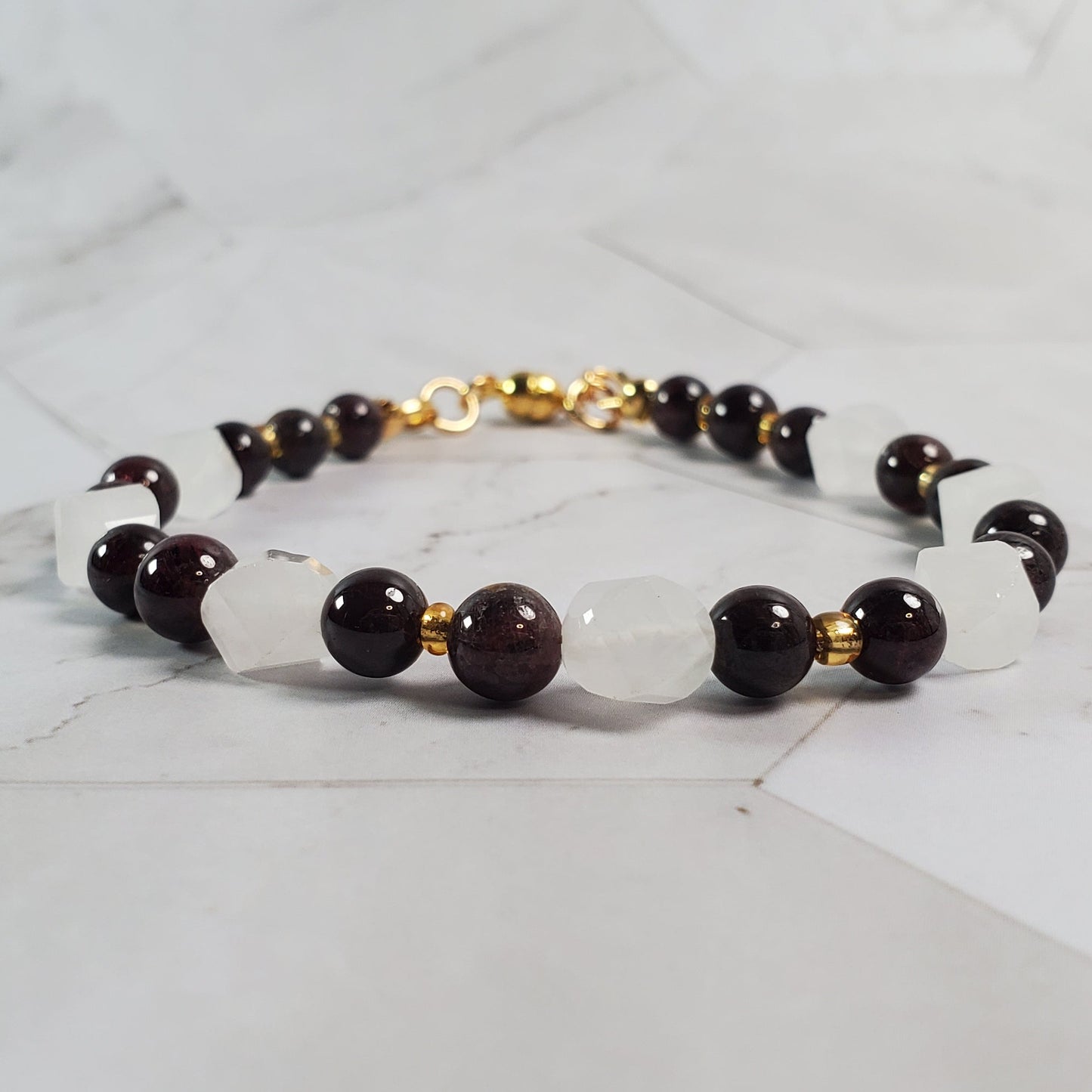 Bracelet red, pink, and gold beads on a marble surface