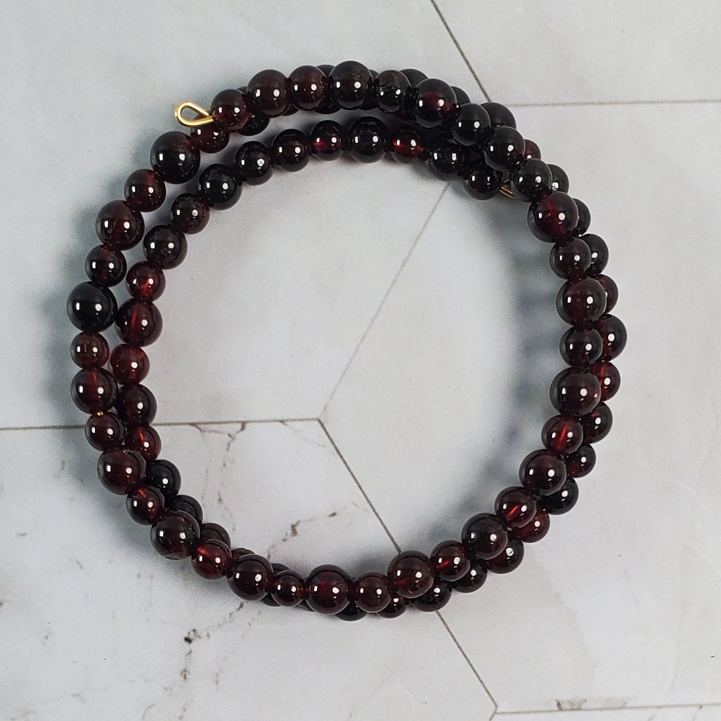 Dark red beaded bracelet on a light marble background
